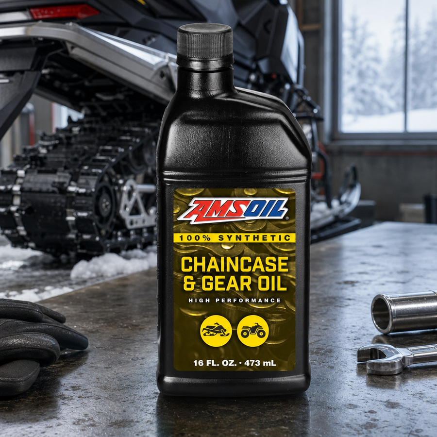 AMSOIL 100% Synthetic Chaincase & Gear Oil staged in a snowmobile and sled workshop