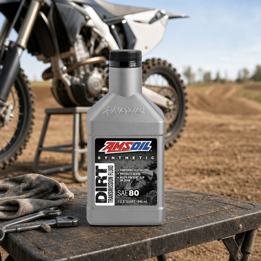 AMSOIL 100% Synthetic Dirt Bike Transmission Fluid staged in a motocross pit area