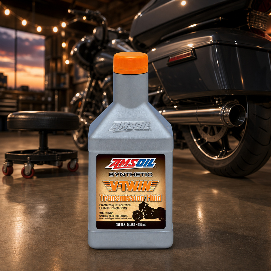 AMSOIL 100% Synthetic V-Twin Transmission Fluid staged in a motorcycle workshop